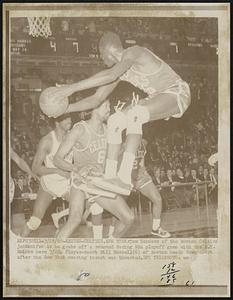 Knicks-Celtics, New York- Tom Sanders of the Boston Celtics jackknifes as he grabs off a rebound during NBA playoff game with the N.Y. Knicks here 3/28. Player-coach Bill Russell (6) of Boston heads down court after the New York scoring thrust was thwarted.