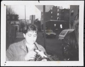 Boy holding a camera on the sidewalk