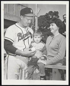 Connie-Sirs and Missus at Bradenton, Fla., training camp of the Boston braves. Connie Ryan (left), veteran infielder of the Braves, who has been very effective in spring training, is showing a baseball to Connie, Jr., while Mrs. Iris Ryan gives a touch of beauty and sentiment to the photo.