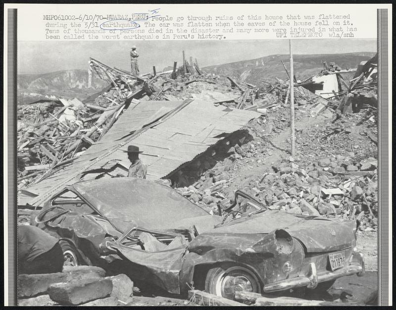 Huaraz, Peru: People go through ruins of this house that was flattened during the 5/31 earthquake. The car was flatten when the eaves of the house fell on it. Tens of thousands of persons died in the disaster and many more were injured in what has been called the worst earthquake in Peru's history.