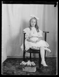 Seated girl with basket of flowers: studio portrait