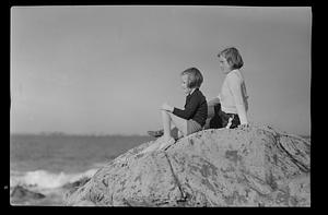 Two girls sitting on a rock at the beach