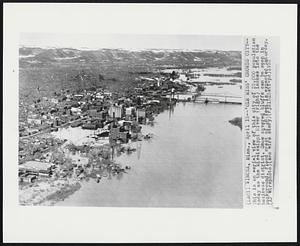 'Ole Miss' Crowds City -- This is an aerial view of this city of 25,000 population today as the Mississippi River (right) inches into the business district. Snow covered bluffs can be seen in background. Flood crest of 18 feet is expected Saturday.