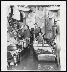 Well Equipped For Flood- Leigh Dawson maneuvers a boat through the flooded display room of the Marine Equipment Company in southwest Washington after the Potomac River overflowed its banks in some parts of the area. Dawson and the other two employes, unidentified, rescued the boat after it was washed from its display cradle outside the store.