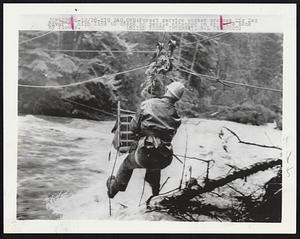 Forest service worker crosses Zig Zag River on high line to check on people stranded on opposite bank by floods.