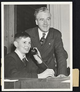 An acting Acting Mayor. That's the position 13-year-old Joseph Robinson of Charlestown, newly elected "Mayor of Boystown," held briefly yesterday when he took over the reins of government during a visit to the mayor's office. He is shown occupying the Mayor's chair, with Acting Mayor John E. Kerrigan at his side and registering keen satisfaction at his performance.
