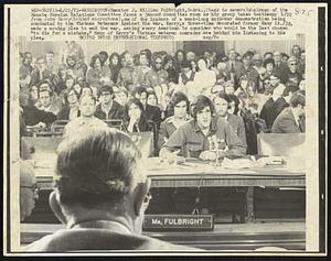 Senator J. William Fulbright, D-Ark., (back to camera) chairman of the Senate Foreign Relations Committee faces a jammed committee room as his group takes testimony 4/22 from John Kerry (behind microphone), one of the leaders of a week-long anti-war demonstration being conducted by the Vietnam Veterans Against the War. Kerry, a three-time decorated former Navy Lt./jg, made a moving plea to end the war, asking every American to consider who would be the last chosen "to die for a mistake." Many of Kerry's Vietnam veteran comrades are behind him listening to his plea.