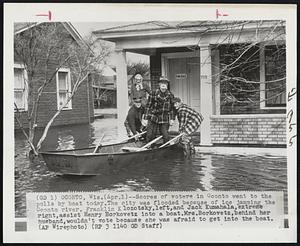 Scores of voters in Oconto went to the polls by boat today. The city was flooded because of ice jamming the Oconto river. Franklin Klozotsky, left, and Jack Kumahala, extreme right, assist Henry Borkovetz into a boat. Mrs. Borkovetz, behind her husband, wouldn't vote because she was afraid to get into the boat.
