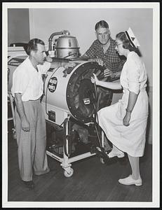 Volunteers Albert Berman, left, and Herbert S. Austin of Wellesley get instructions on manual operation of tank respirator from Nurse Margaret Kilcoyne at the Mary MacArthur Respirator Center in Wellesley. the center is taking no chances on power failure.