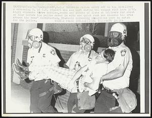 Columbia Police carry off to the sidelines a screaming U. of S.C. student who was hurt during the campus riot here 5/12. Angry students threw bottles, rocks and pieces of slate at officers for about an hour before the police moved in with one quick rush and cleared the area around the men's dormitories. Students screaming obscenities were no match for the police.
