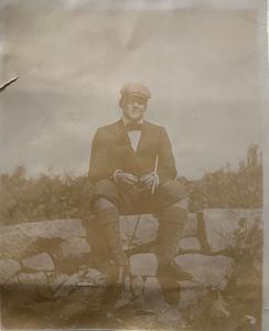 Unidentified man sitting on stone wall in Yarmouth Port, Mass.