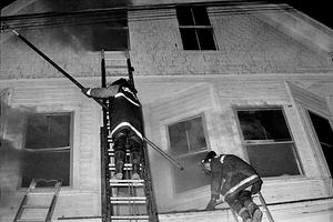 Firefighters Bob Kinsella and John Dodd scaling ladders to vent the third floor