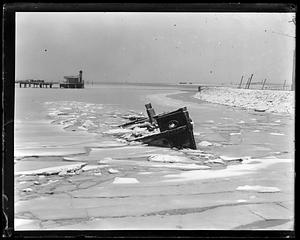 An unidentified item, possibly a boat, sinking in icy body of water