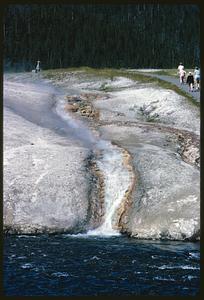 Steam rising from waterfall by path and forest, Yellowstone National Park