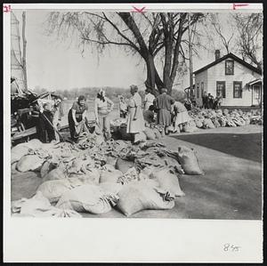 Housewives Battle River-These Clinton housewives turned out to build a sandbag levee to protect their homes from the flooding Mississippi river, which can be seen in the background. Their efforts ultimately failed when the river cut around the dike.