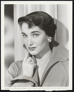 Julie Adams, proclaimed a couple of years ago as "the girl with the most perfect legs in Hollywood," thereafter made eight films in a row in which she wore period costumes and flowing skirts, hiding her legs and figure. Now, at last she has two modern roles in a row coming up. She stars for U-I with Tony Curtis and George Nader in "Six Bridges To Cross," thrilling story of Boston's $2,500,000 robbery - after which Julie will star with Rory Calhoun and Ray Danton in "The Looters," another modern melodrama.