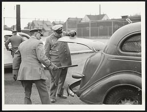 Metropolitan district police searching an automobile outside an Everett oil plant yesterday, before permitting it to enter the grounds. Rioting occurred there Tuesday.