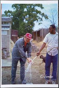 Manager Charles Jackson helping owner Charles McQuiggan clean his hands in front of front barn