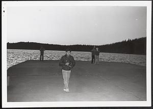 Young man standing with a camera near the water