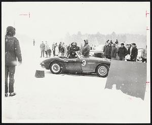 Despite seventeen degree temperature and steady snowfall hardy sports car drivers participated in a rally on the bleak icy runway of the North Newport, New Hampshire Airport. Here a driver checks in with officials at the finish line. All drivers are clocked and cars leave one at a time.