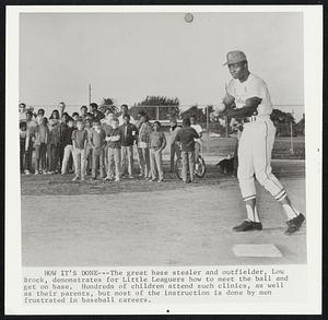 How it's Done-- The great base stealer and outfielder, Lou Brock, demonstrates for Little Leaguers how to meet the ball and get on base. Hundreds of children attend such clinics, as well as their parents, but most of the instruction is done by men frustrated in baseball careers.