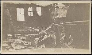 Interior of burned building after fire, with firemen present