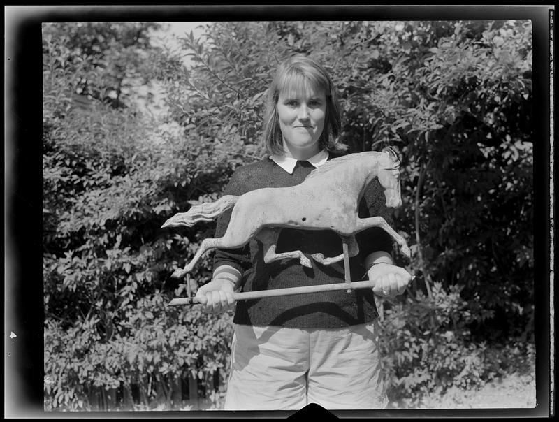 Girl posing with horse sculpture in garden