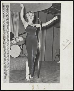 Errol Flynn Protege in Night Club Debut--Beverly Aadland, 17-year-old protege of the late Errol Flynn, makes her night club singing debut, at the Sundown in Hollywood last night. She sang a variety of numbers in a voice that appeared to please the audience, but had to quit at ten o'clock--a condition made by the State Labor Board in issueing her a work permit as a minor.