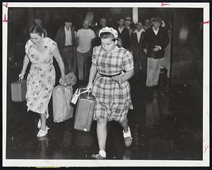 Two women walking in the rain holding suitcases and a bag