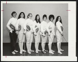 Seven women standing in a line holding fencing gear