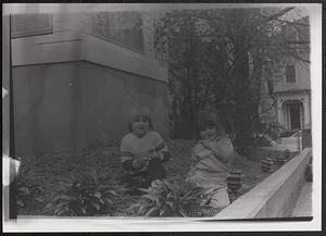 Two children sitting in a garden bed