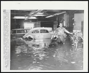 Washed Out of Business--Bodyman stands in knee-deep water in this Providence Auto Body Shop that was completely flooded today after heavy rains flooded most of the city.