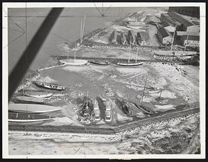 Yachts Worth Millions caught in ice packs of George E. Lawley yard here. Yankee and Rainbow, former cup defenders, are under winter covers at lower left.