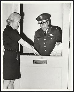 Secretary at Copley Square draft office, Miss Ann Heron and Army Reserve officer Maj. Walter Cavanaugh examine broken window of office door.