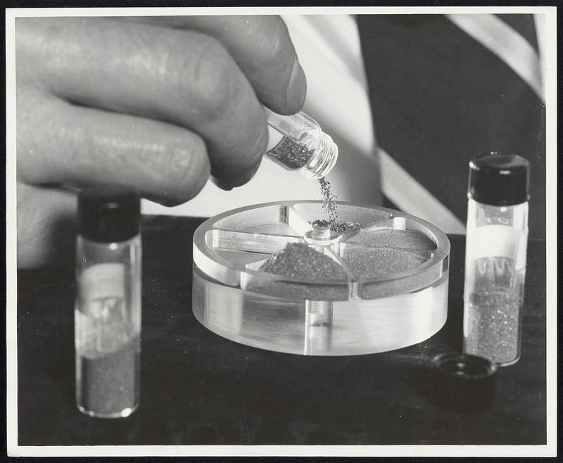 100 Carats of Man-Made Diamonds. General Electric scientist pours man-made industrial diamonds into a container for presentation to the Smithsonian Institution. A plaque commemorating GE's production of diamonds in 1954 was presented today (May 3, 1956) to the Smithsonian by Dr. C. G. Suits, GE vice president and director of research. The exhibit consists of a cluster of some of the first tiny diamonds madde in the Research Laboratory, surrounded by 100 carats of man-made industrial diamonds, produced in a pilot plant at GE's Carbology Department in Detroit. GE is now in limited production of the industrial-type stones. Importance of diamonds to U.S. industry was stressed by Suits in making the presentation of the historic stones to the Smithsonian. The availability of the man-made stones will have "an important impact on American industry and defense," he predicted, adding that recent progress in translating "a laboratory achievement into a commercial process" will give the U.S. an independent supply of a vital raw material for which it is now wholly dependent on imports.