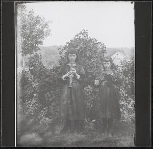 Two girls playing oboe and violin in backyard