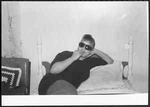 Young woman lying on bed with sunglasses