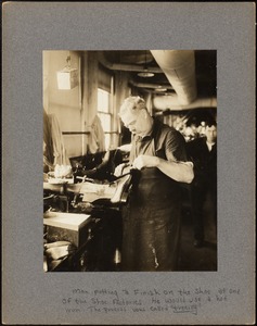 Man putting a finish on the shoe at one of the shoe factories. He would use a hot iron. The process was called "treeing"