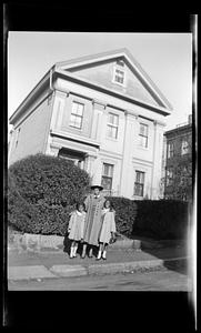 Vivian and two girls pose in front of a house and shrubs