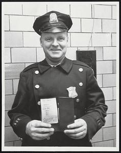 Patrolman Gerald Abbot, who captured suspect in attempted bank holdup, holds note that says "Happy Seasons Hold Up!! Give me 100$, 50$, 20$, 10$ quick. Don't push alarm."