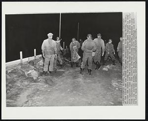 On Through the Night -- Soldiers of the 201st and the 199th Engineer Battalions from Camp McCoy, Wisc., bolster the dikes along the rising Missouri River here tonight as they race against time and the rising water in their battle to save the city from inundation. The hastily erected wooden barrier, erected today atop the earthen dikes, was being reinforced with sandbags and dirt to hold back the water.