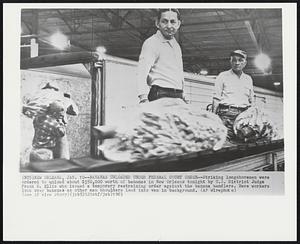 New Orleans -- Bananas Unloaded Under Federal Court Order -- Striking longshoremen were ordered to unload about $350,000 worth of bananas in New Orleans tonight by U.S. District Judge Frank B. Ellis who issued a temporary restraining order against the banana handlers. Here workers look over bananas as other man shoulders load into van in background.