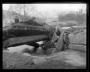 Car wrecked under a bridge, hood in water underneath