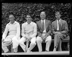 Two tennis players sitting next to two men in suits