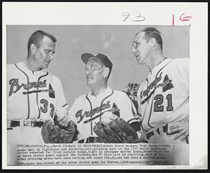 Back in Uniform-Milwaukee Brave manager Fred Haney, center, hands ball to rightander Lew Burdette, left, pitching hero of the 1957 World Series, as latter reported for first workout today. Right is southpaw Warren Spahn. Burdette, winner of three Series games against the Yankees, was 20 days late in reporting. Most of the other pitching mates have been working out since Feb. 22. Lew had been a holdout since then. Spahn was winner of the other Series game for Braves.