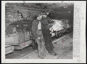 Lafayette, Colo -- Coming Up -- Maintenance workers Tony Rich (left) and Everett Billington pause to reread news of the end of the coal strike as they work to bring coal from the black diamond mine in Northern Colorado to the surface to get up steam to resume full production Monday.