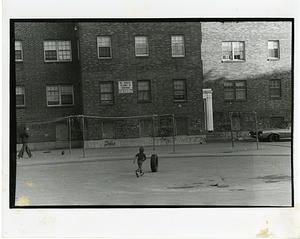 Boy rolling a tire across a courtyard