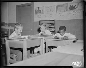 Three young boys reading at desks