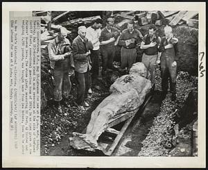 Cooperstown, N.Y. -- Workmen stand in mock reverence at the side of the famed Cardiff Giant, sensational American hoax of 1869, in an open grave at the Farmers’ Museum here. The stone giant, measuring 10 feet, 4½ inches and weighing 2,990 pounds, was brought here from Des Moines, Iowa to be added to New York’s historical collection.