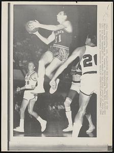 Driving for Two--John Egan (11) of the Baltimore Bullets goes up between Philadelphia 76ers Bill Melchionni (28) and Dave Gambee (20) for a basket in the first period of their NBA game in Philadelphia Convention Hall.